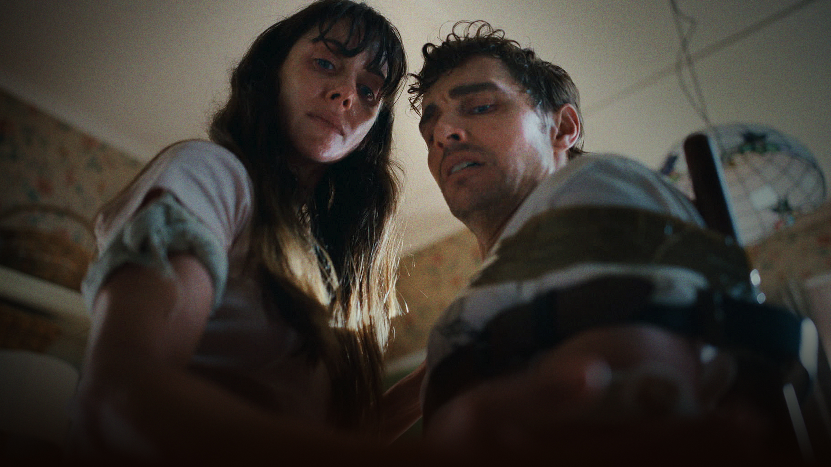 二人が緊迫した表情で手を伸ばし何かをしようとしている。